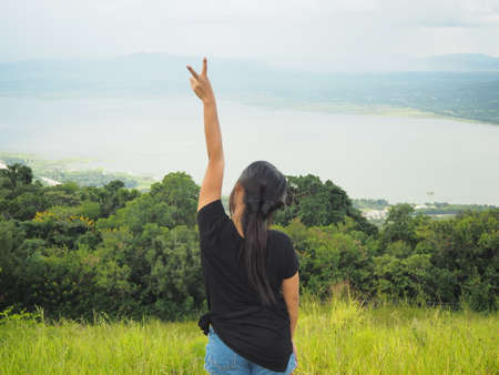 Woman stand in natural feeling happy show hand up with mountain and lake background