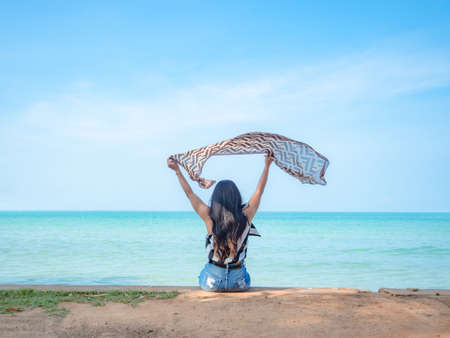 Travel woman sit relax at the beach and show scarf up and blue ocean blue sky beautiful landscape,Travel and relax at the beach on holiday conceptの写真素材