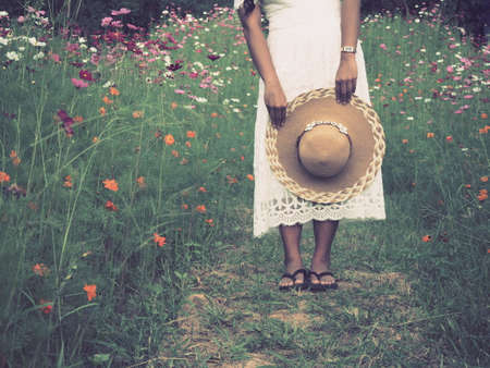 Traveler woman standing in flower park and holding hat with beautiful view,Asian woman traveler white dress in flower gardenの写真素材
