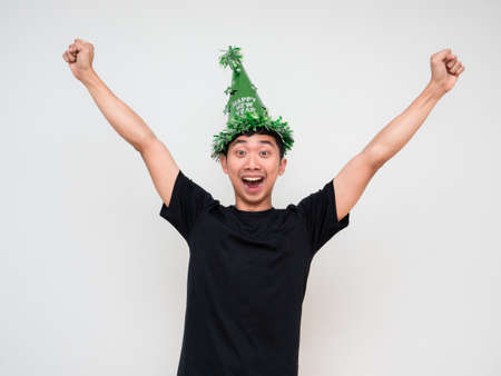 Young man happy and cheerful look at camera show arm and fist up with green hat and tassel colorful on white isolated happy new year concept celebrationの写真素材