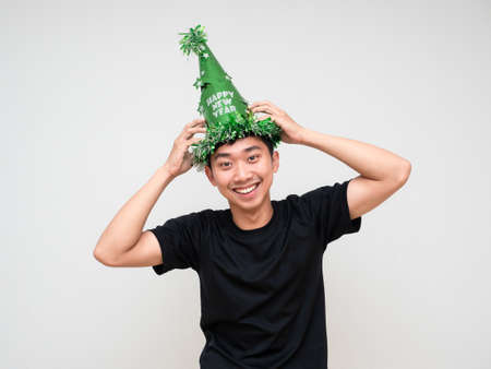 Young man black shirt touch green hat on head happy smile look at camera on white background...