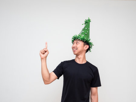 Portrait young man happy face with green hat point right finger above look at right hand and smile on white isolated backgroundの写真素材