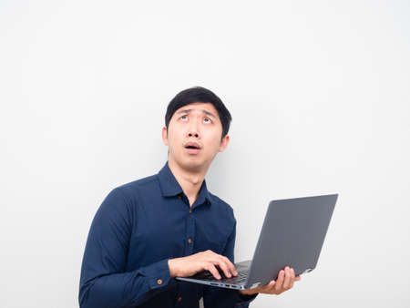 Asian man holding laptop feeling shocked looking up at copy spaceの写真素材