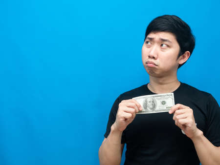 Asian man holding money in hand feeling sad emotion lookint at copy space poor man conceptの写真素材