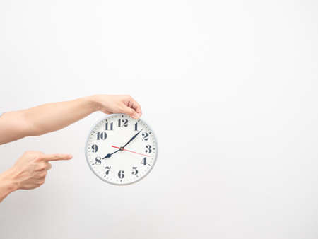 Hand point finger at analog clock copy space white isolated