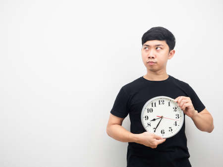 Man holding analog clock feeling unhappy and looking at copy spaceの写真素材