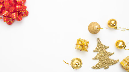 Golden christmas accessories  and red ribbon on white background top view copy spaceの写真素材