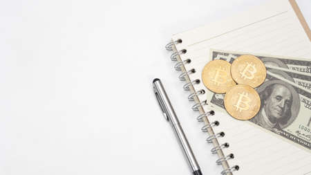 Gold bitcoin dollar money and pen with notebook on the table top view copy space
