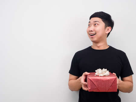 Cheerful man holding gift box and looking at copy space white background