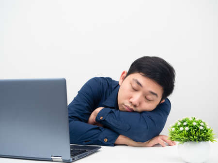 Asian man sleep with his laptop on the table tried about work from homeの写真素材