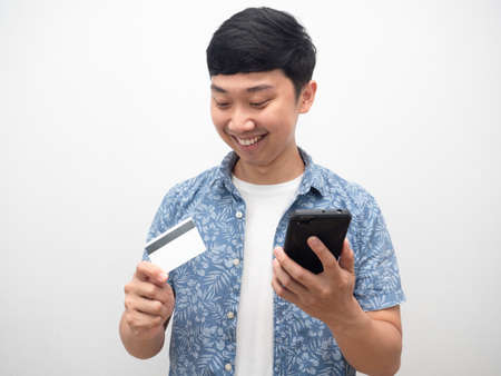 Man holding mobile phone and looking at credit card in hand happy smileの写真素材
