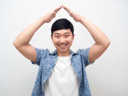 Cheerful asian man smiling gesture hand roof house portraitの写真素材