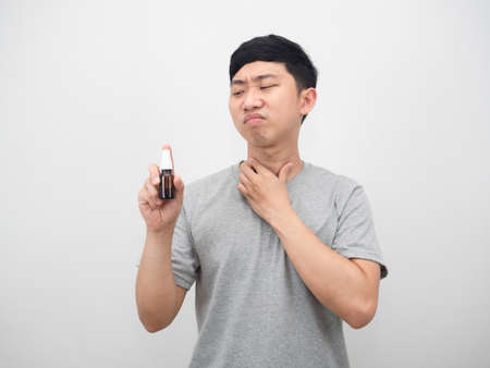 Asian man feeling sore throat and looking at throat spray in handの写真素材