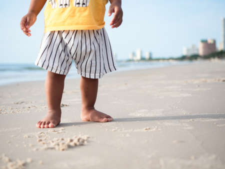 Close up feet of kid standing on the beach with beautiful ocean backgroundの写真素材