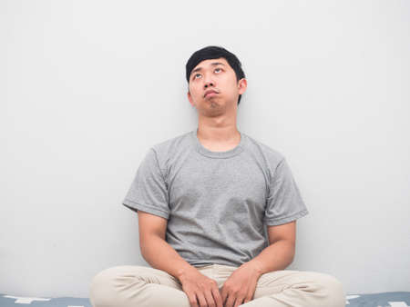 Man sit on the bed bored emotion looking up white backgroundの写真素材