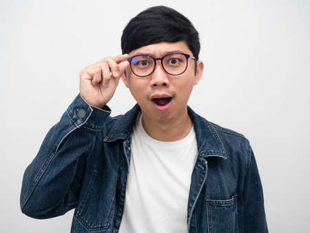 Asian man jeans shirt touch glasses amazed emotion studio shotの写真素材