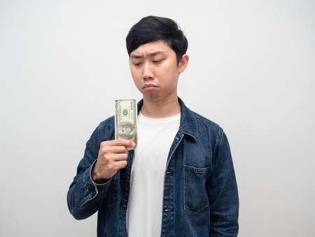 Man jean shirt looking at little money in hand feel unhappy,Poor man holding moneyの写真素材
