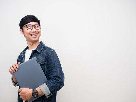 Positive man jeans shirt holding laptop smile turn face looking at copy spaceの写真素材