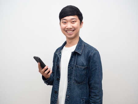 Cheerful man jeans shirt smile holding smartphoneの写真素材