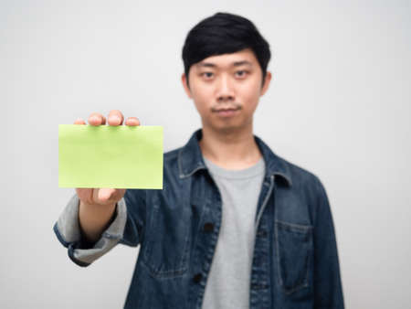 Positive young man jeans shirt holding empty post it white backgroundの写真素材