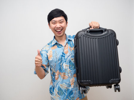 Cheerful man happy smile holding laggage and thumb up isolatedの写真素材
