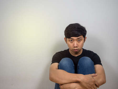 Tried man sit hug knee feels hopeless looking at camera copy spaceの写真素材