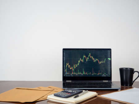 Laptop nusiness graph screen on workspace table white backgroundの写真素材