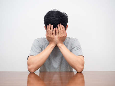 Depressed man sit close face at his working table white backgroundの写真素材
