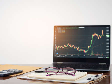 Laptop financial graph on workspace table white background