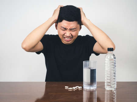 Sickness man  feels headache with medicine and water on table