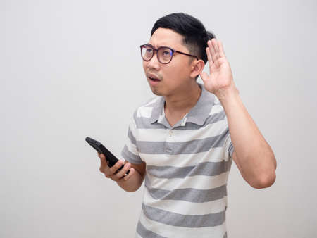 Young man wearing glasses hold cellphone gesture listening can't not hearの写真素材