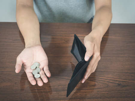 Man hands hold empty wallet no money with coins on the table