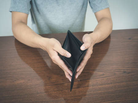 Man hands hold empty wallet no money on the tableの写真素材