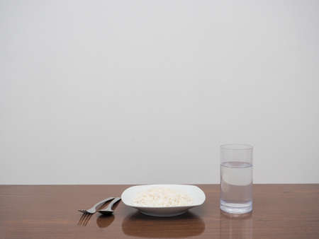 Dish of rice and cutlery with glass of water  on the table copy spaceの写真素材