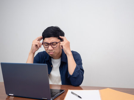Businessman sitting at working table feels tried and headache about work hard