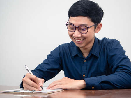 Asian businessman writing on document at the desk feels happy with his workingの写真素材