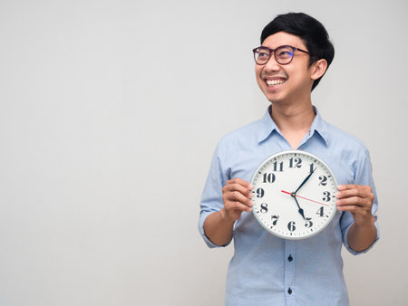 Asian businessman happy smile holding analog clock gesture looking isolatedの写真素材