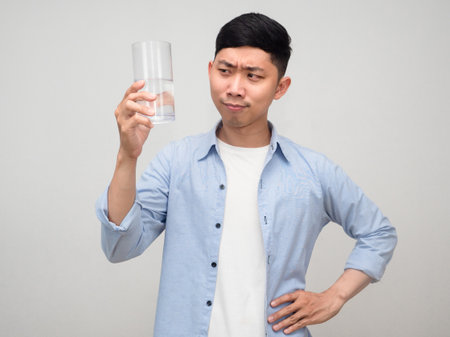 Healthy positive man looking at glass of water in his hand isolatedの写真素材