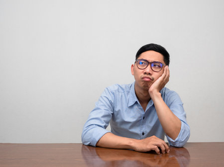 Asian bisinessman sit alone at table feels bored and triedの写真素材