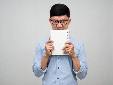 Young manager man holding the book close his face looking at you isolatedの写真素材