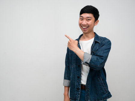 Positive man jeans shirt happy smile gesture point finger copy space isolatedの写真素材
