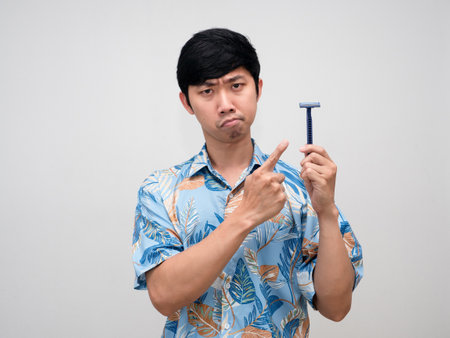Asian man beach shirt point finger at shaving in hand feels doubt isolatedの写真素材