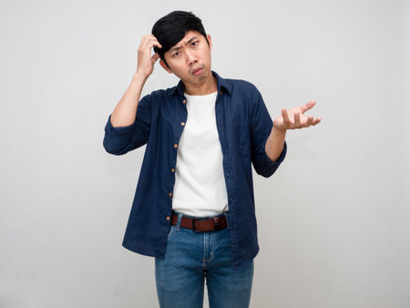 Asian man standing gesture scratch head feels doubt and confused isolatedの写真素材