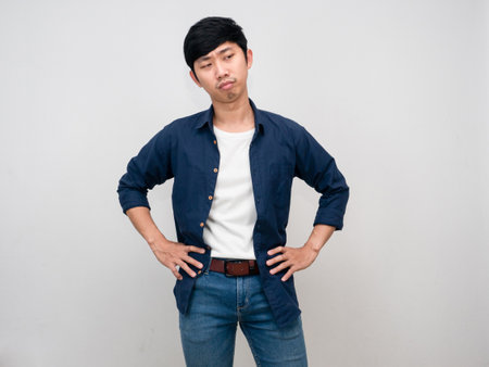 Thai man standing hands at waist feels bored and tried isolatedの写真素材