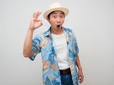 Tourism asian man wearing hat beach shirt cheerful show hand ok isolatedの写真素材