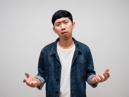 Negative asian man jeans shirt feels tried and confused about working isolatedの写真素材