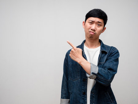 Negative asian man jeans shirt feels confused and doubt gesture point finger isolatedの写真素材