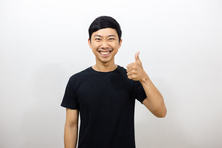 Positive asian man black shirt smile show thumb up isolatedの写真素材
