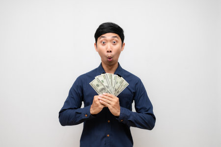 Asian man earn a lot of money in his hand feels amazed isolatedの写真素材