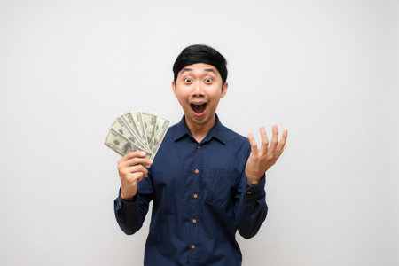 Asian man feels shocked about earn money in his hand isolatedの写真素材